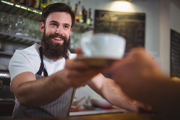 Cameriere che serve una tazza di caffè al cliente