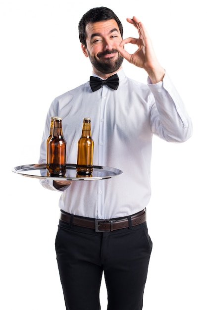 Cameriere con bottiglie di birra sul vassoio che fanno OK segno