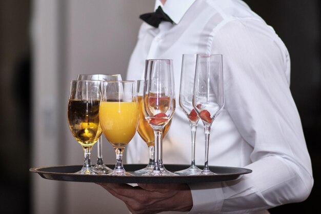 Cameriere con un vassoio di bevande succhi di vino e champagne a una festa