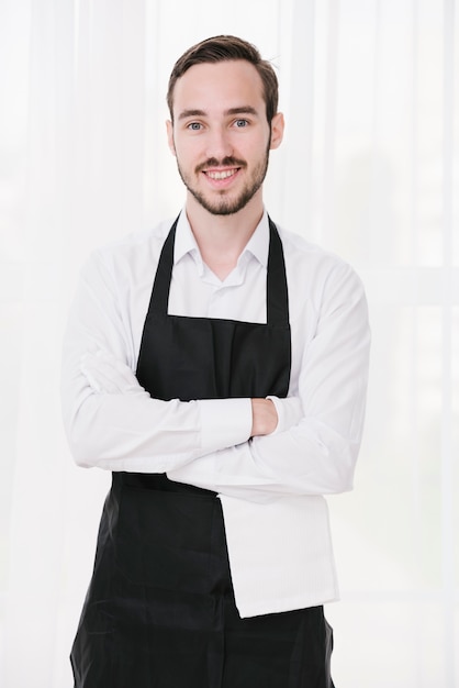 Cameriere felice in piedi con le mani incrociate