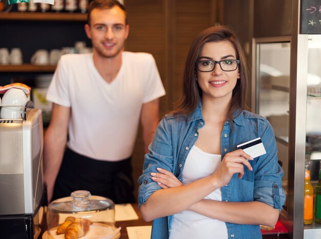 Cameriere sorridente e bella cliente femminile con carta di credito