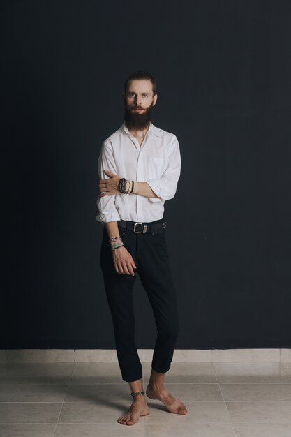 Camicia bianca dell'uomo barbuto di stile hipster in studio su fondo nero