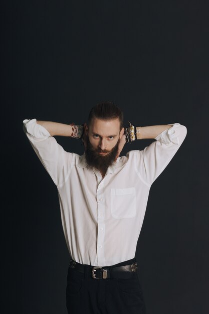 Camicia bianca dell'uomo barbuto di stile hipster in studio su fondo nero