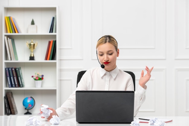 Camicia da ufficio ragazza bionda carina servizio clienti con auricolare e pensiero al computer