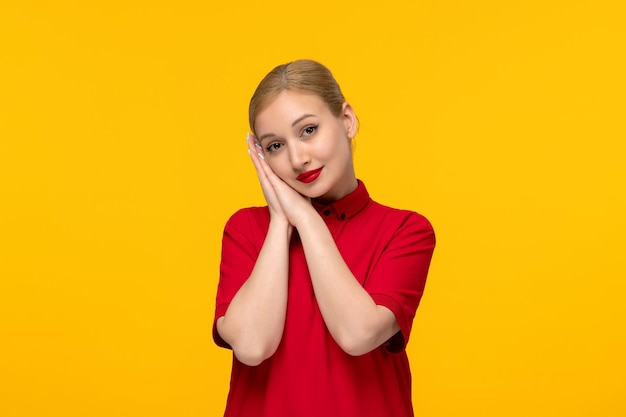 Camicia rossa giorno bella ragazza che mostra il gesto del sonno in una camicia rossa su sfondo giallo