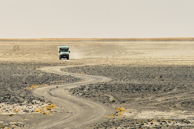 Camion che guida attraverso una strada rocciosa sinuosa che fa polvere