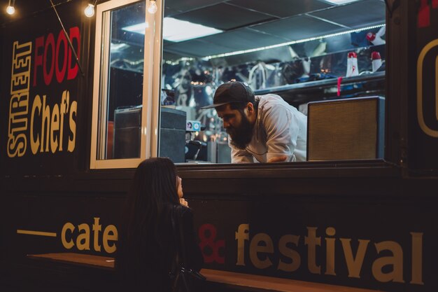 camion di cibo con hot dog e hamburger. Chef barbuto brutale