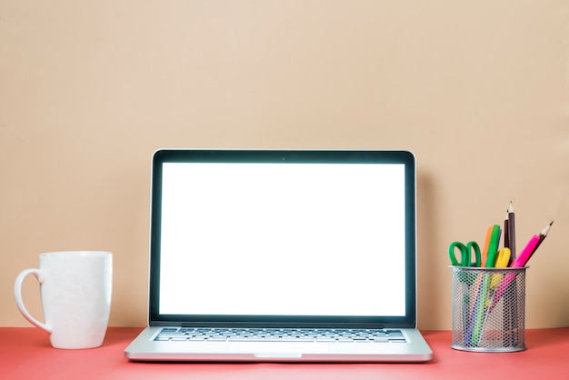 Cancelleria e tazza vicino al computer portatile