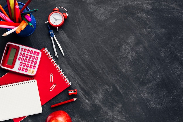 Cancelleria rossa vicino a orologio e apple sulla lavagna