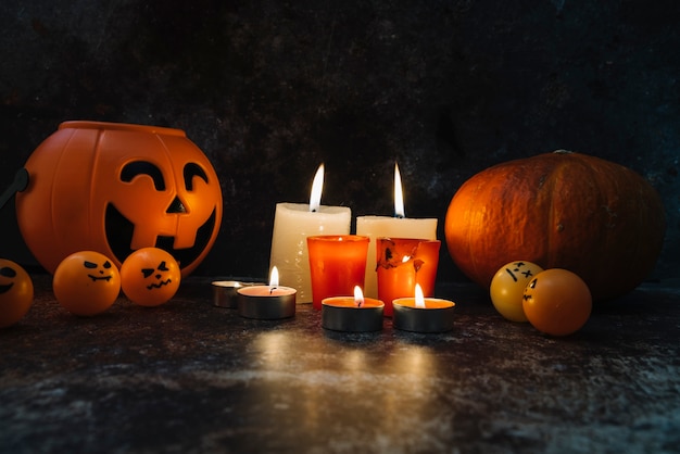 Candele accese in piedi tra cesto arancione e zucca e palle nella foto