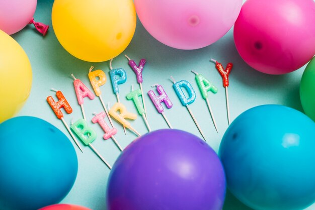 Candele di buon compleanno bastone circondato con palloncini colorati