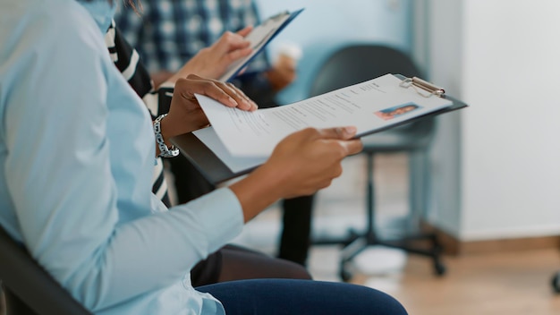 Candidata seduta in coda e che riceve file cv, in attesa di iniziare un colloquio di lavoro sull'opportunità di carriera. Donna che si prepara a partecipare alla riunione di reclutamento con il dipendente delle risorse umane.