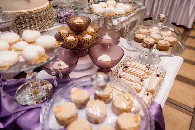 Candy bar con dolci mousse, bignè e pasticceria sul tavolo viola