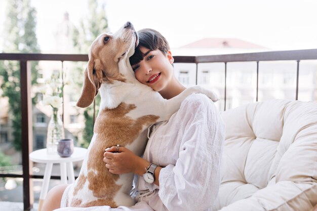 Cane beagle carino che abbraccia la ragazza dai capelli neri per esprimere fedeltà