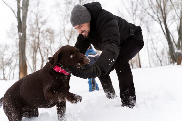 Cane che gioca con il bambino nella neve con la famiglia