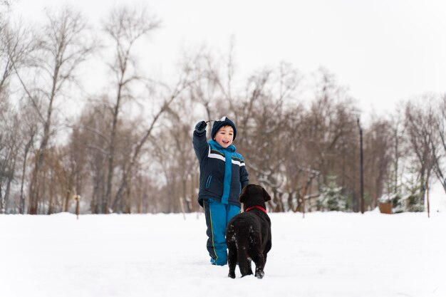 Cane che gioca con il bambino nella neve con la famiglia