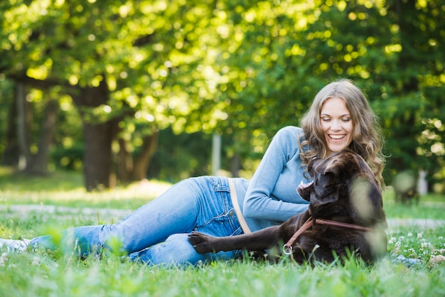 Cane con il proprietario dell&#39;animale domestico che si siede nel parco
