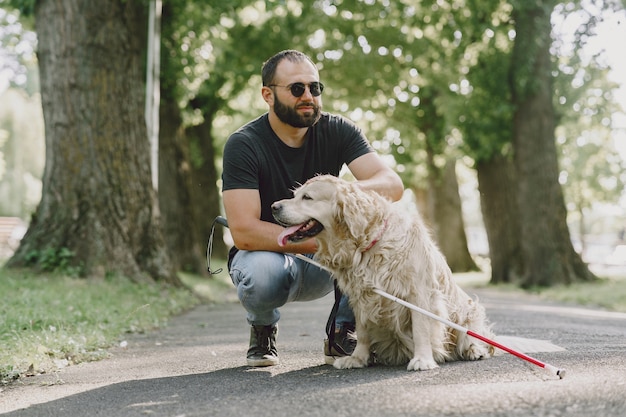 Cane guida che aiuta un cieco in città. Bel ragazzo cieco riposare con il golden retriever in città.