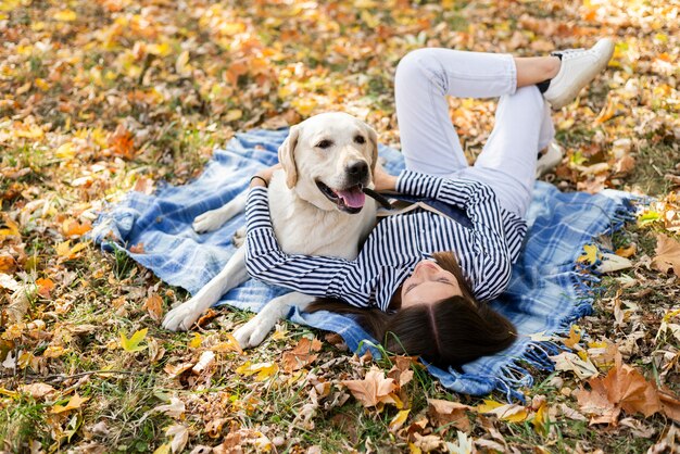 Cane sveglio con la giovane donna che si siede su una coperta