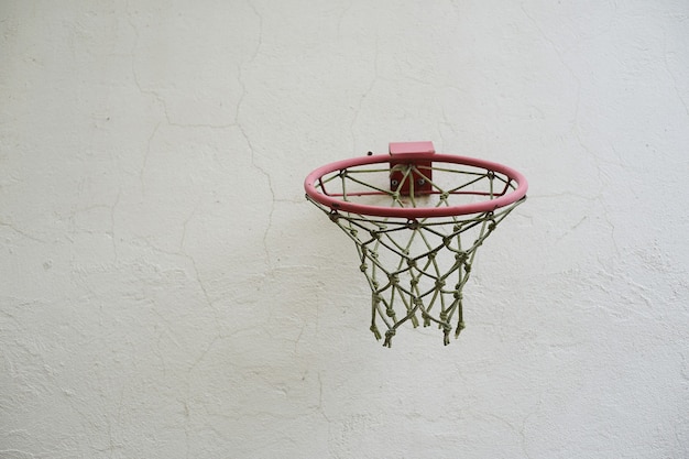 Canestro da basket con rete contro un muro bianco all'aperto