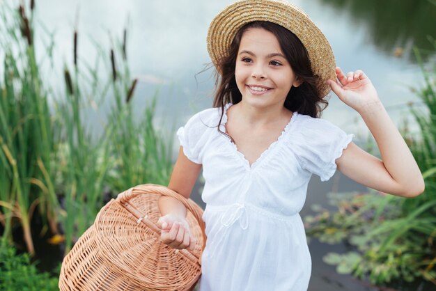 Canestro di picnic della tenuta della ragazza dal lago