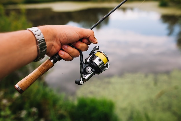 Canna da pesca della holding della mano del pescatore all&#39;aperto