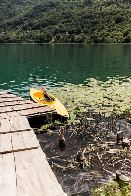 Canoa galleggiante vicino al molo di legno sul lago