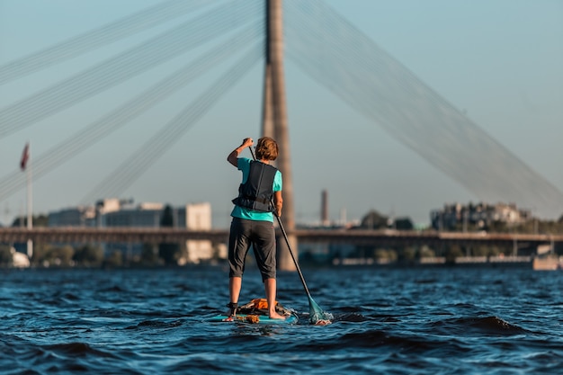 Canottaggio femminile con paddle board SUP lungo il fiume