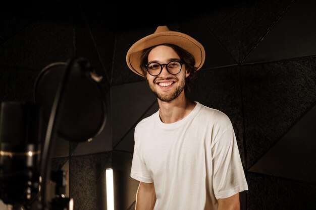 Cantante maschio alla moda bello che guarda felicemente nella canzone di registrazione della macchina fotografica per il nuovo album in studio del suono