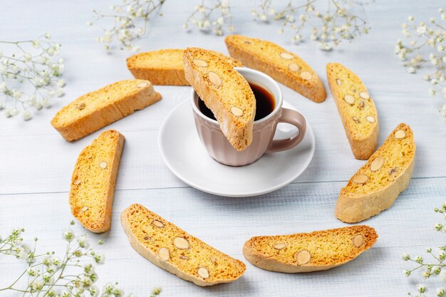 Cantuccini tradizionali toscani dei biscotti italiani con le mandorle, una tazza di caffè su luce