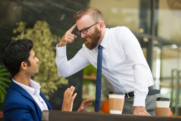 Capo barbuto instabile che gesturing alla testa mentre gridando