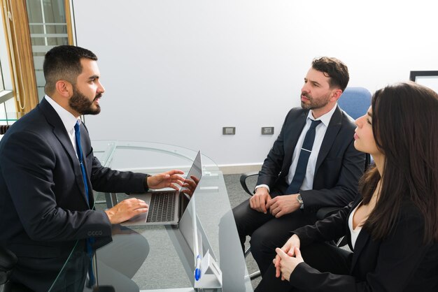 Capo bello che parla di produttività e nuove attività lavorative con i suoi dipendenti professionisti nel suo ufficio in un business center