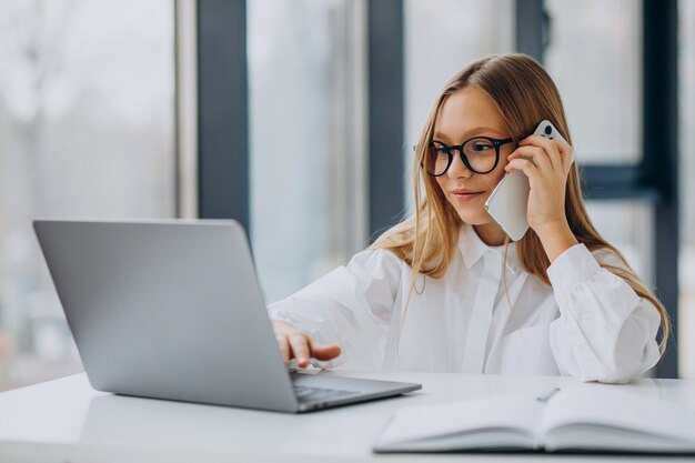 Capo del bambino utilizzando laptop e parlando al telefono