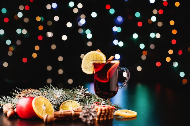 Capodanno e decorazioni natalizie. Gli occhiali con vin brulè stanno sul tavolo con le arance, le mele