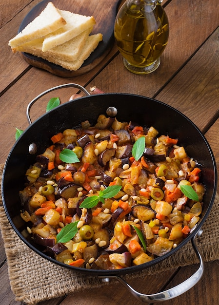 Caponata italiana con padella su un tavolo di legno