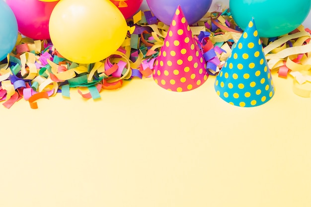 Cappelli da festa vicino a palloncini su coriandoli