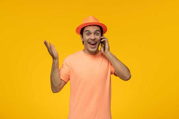 Cappello arancione carino giovane ragazzo in maglietta arancione con il cappello parlando al telefono e ridendo