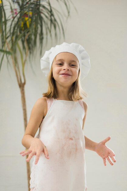 Cappello bianco da portare sorridente del grembiule e del cuoco unico della bambina