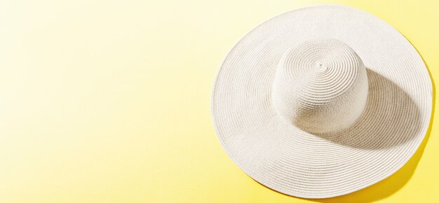 Cappello di paglia su fondo soleggiato giallo luminoso