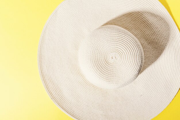 Cappello di paglia su uno sfondo giallo brillante e soleggiato