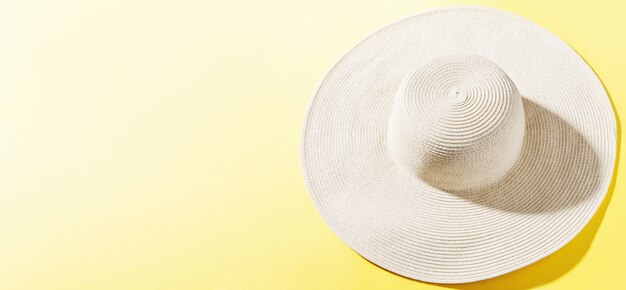 Cappello di paglia su uno sfondo giallo brillante e soleggiato
