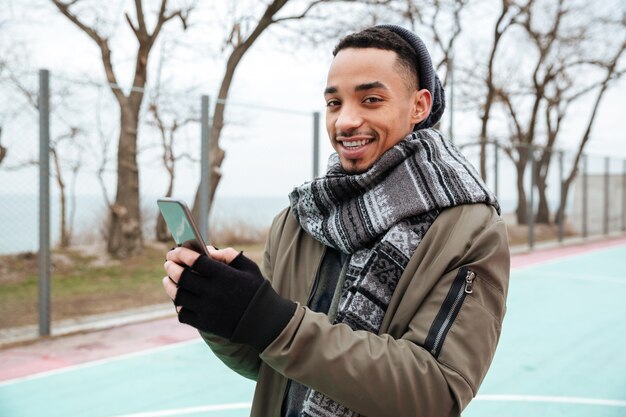 Cappello e sciarpa da portare dell'uomo africano che chiacchierano dal telefono.