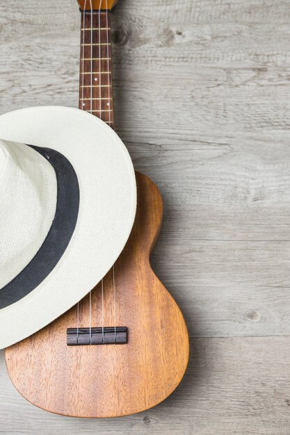 Cappello sopra la chitarra di legno contro il contesto di legno della plancia