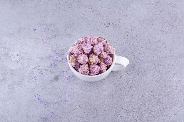 Caramella di popcorn viola servita in una tazza da tè su sfondo marmo. Foto di alta qualità