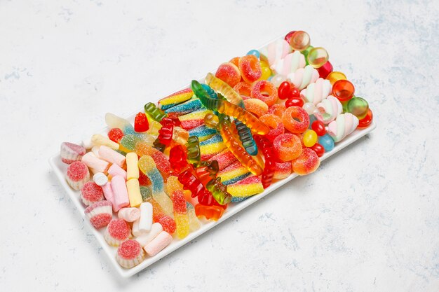 Caramelle colorate, gelatina, marshmallow sulla superficie della luce. Vista dall'alto con spazio di copia