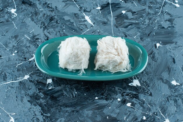 Caramelle di cotone turche tradizionali su un piatto, su sfondo blu.