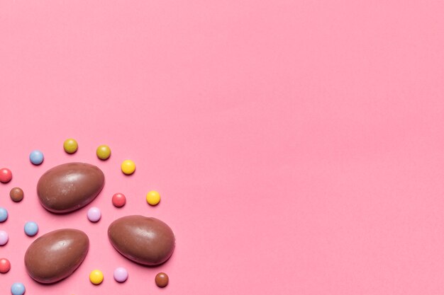 Caramelle di Pasqua uova di cioccolato e gemma con lo spazio della copia per la scrittura del testo su sfondo rosa