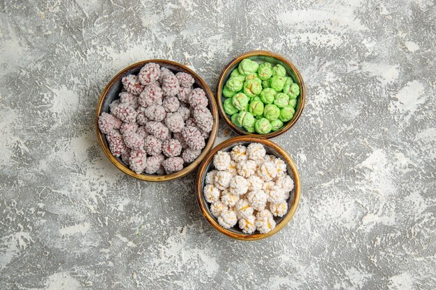 Caramelle di zucchero di vista superiore all'interno dei piccoli piatti sul biscotto dolce del tè del bonbon di zucchero candito del fondo bianco