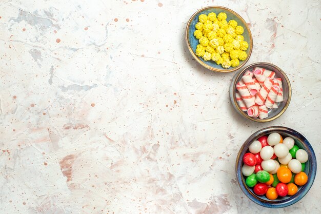 Caramelle dolci di vista superiore con confitures sulla caramella di zucchero di colore dell'arcobaleno della tabella bianca