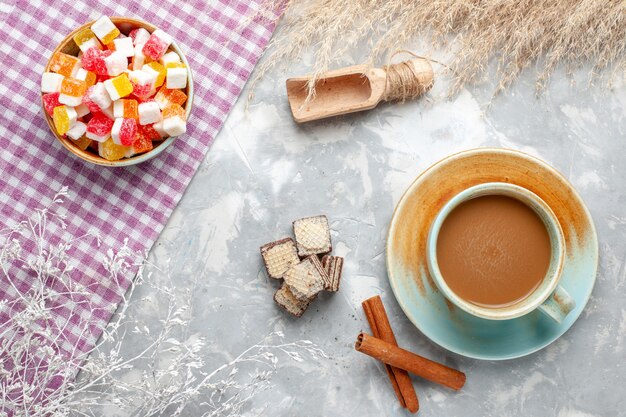 Caramelle dolci vista dall'alto con cannella e caffè al latte sullo sfondo chiaro colore della foto zucchero candito dolce